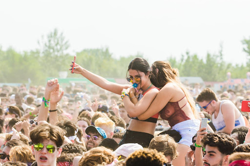 two girls hugging at music festival; wristbands